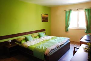 Un dormitorio con una cama con paredes verdes y una ventana en Vinařství Pastorek, en Čejkovice