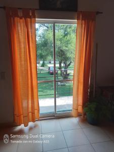 a window with orange curtains and a view of a yard at Nancy's Residencias in Santa Rosa de Calamuchita