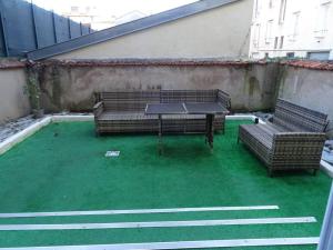a patio with two benches and a table on grass at Appartement Artem neuf et terrasse in Nancy
