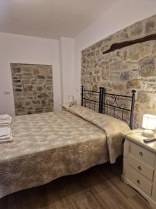 1 dormitorio con cama y pared de piedra en Agriturismo Nonno Ninuccio, en Gioi