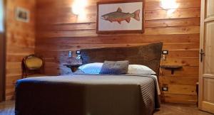 a bedroom with a bed with a wooden wall at Trout Lodge in Collagna
