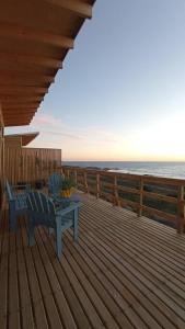 una terrazza in legno con panchina blu sulla spiaggia di Cabaña Orca Lodge Norte frente al mar en Curanipe, Desconéctate para reconectar a Curanipe
