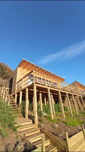 una casa costruita su una collina con scale in legno di Cabaña Orca Lodge Norte frente al mar en Curanipe, Desconéctate para reconectar a Curanipe