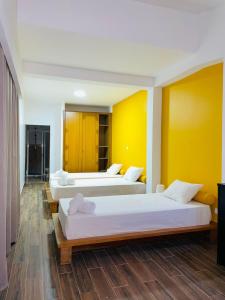 2 camas en una habitación con paredes amarillas en Residencial Sol Point Art, en Ponta do Sol