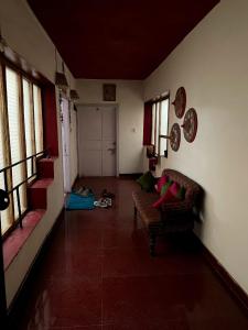 a living room with a couch and a hallway with windows at OOTY ACHY APARTMENT COTTAGE in Ooty