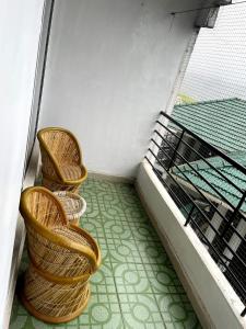 a balcony with two wicker chairs and a table at OOTY ACHY APARTMENT COTTAGE in Ooty