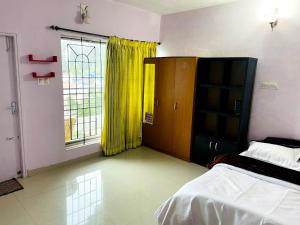 a bedroom with a bed and a window with yellow curtains at OOTY ACHY APARTMENT COTTAGE in Ooty