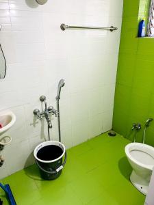 a green bathroom with a toilet and a bucket on the floor at OOTY ACHY APARTMENT COTTAGE in Ooty