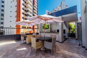 un patio con mesa, sillas y sombrillas en Apt Lindíssimo com Piscina e Climatização, en Salvador