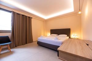 a bedroom with a bed and a chair and a window at Mini Suites Free shuttle from and to Athen's Airport in Spata