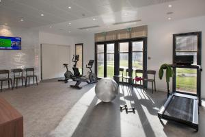 een fitnessruimte met fitnessapparatuur in een kamer met ramen bij Domitys La Palangre in Le Tréport