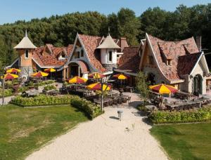 ein großes Gebäude mit Tischen und Sonnenschirmen davor in der Unterkunft Villa Wolde, Luxe villa (10p.) met Hottub in Zeewolde