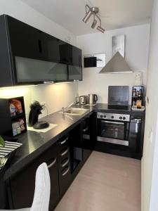 a kitchen with black cabinets and a sink and a stove at Ferienwohnung CASA GELI in Glücksburg