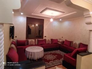sala de estar con sofá rojo y mesa en Maison Lahoucine, en Sidi Ifni