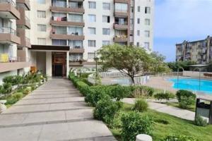 a walkway in front of a building with a swimming pool at Departamento moderno, vista al mar y estacionamiento incluido in Antofagasta