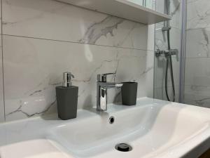 a bathroom sink with two cups on top of it at City Luxe Apartment in Čakovec