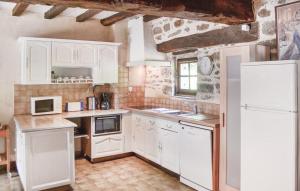 La cuisine est équipée de placards blancs et d'un réfrigérateur blanc. dans l'établissement Les 3 rossignols, à Taden