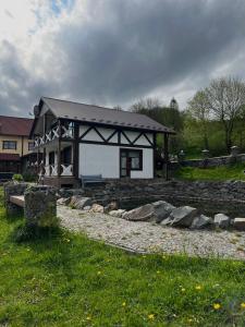 une petite maison avec un mur en pierre devant elle dans l'établissement Готельно-Ресторанний комплекс Кичера, à Volovets