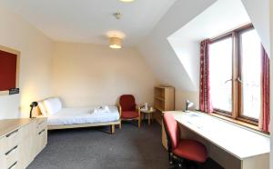 um quarto com uma cama, uma secretária e uma janela em Selwyn College, Cambridge em Cambridge