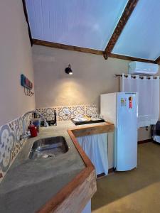 a kitchen with a sink and a refrigerator at Quinta dos Laranjais Chalés in Viçosa do Ceará