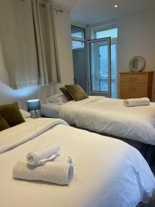 a room with three beds with towels on them at Park View Homestay in Barking