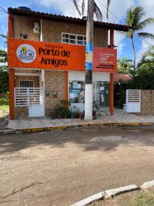 a store with an orange sign in front of a building at Pousada Porto de Amigos in Porto De Galinhas