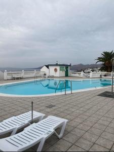 una piscina con 2 sillas blancas al lado en Lazydays en Puerto del Carmen