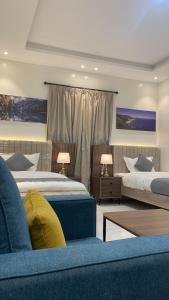 a bedroom with two beds and a blue couch at شقق ثمانين بارك 2 in Khamis Mushayt