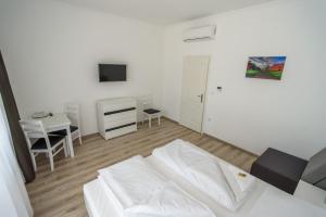 a living room with a white bed and a desk at BL Garden Panzió in Balatonlelle