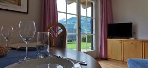 a dining table with two wine glasses and a television at Appartements Mary inklusive Tauern-Spa Kaprun in Kaprun