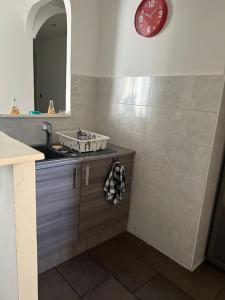 baño con lavabo y reloj en la pared en Superbe appartement avec parking gratuit, en Vaulx-en-Velin