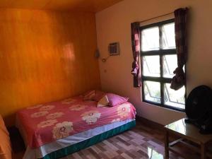 Habitación pequeña con cama y ventana en Shey's Travellers Inn, en Mambajao