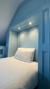 łóżko z białą poduszką w niebieskim pokoju w obiekcie The Fairhaven Hotel w mieście Weymouth
