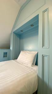 a bedroom with a white bed with a blue wall at The Fairhaven Hotel in Weymouth