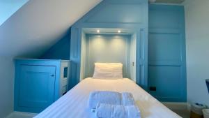 a blue room with a bed with two towels on it at The Fairhaven Hotel in Weymouth