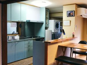 una cocina con armarios azules y una mesa con sillas en Folksy House / Vacation STAY 64171 en Izumo