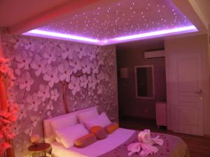- une chambre avec un lit et un mur violet orné de fleurs dans l'établissement Studio Love Spa Baignoire XXL Port Vieux La Ciotat, à La Ciotat
