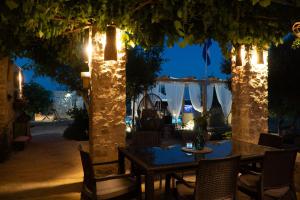 a patio with a table and chairs under two trees at night at Opg Pelejš in Pag