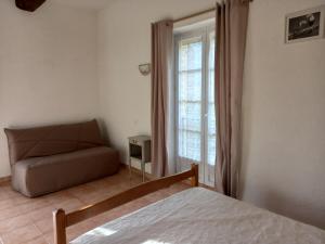 1 dormitorio con cama, sofá y ventana en Chambres d'hôtes Domaine de Pélissols, en Bédarieux