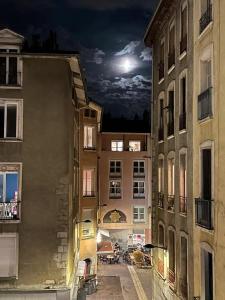 a view of a city at night with a full moon at Chambre spacieuse dans magnifique appartement XVII in Grenoble
