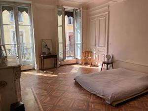 a bedroom with a bed in a room with windows at Chambre spacieuse dans magnifique appartement XVII in Grenoble