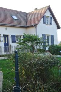 Casa blanca con ventanas azules y palmera en Gîte Les Chênes, en Villeneuve-les-Sablons