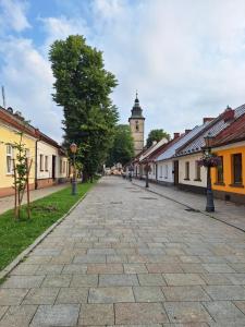 a cobblestone street in a town with a clock tower at Chwile w Starym Sączu, sauna i beczka in Stary Sącz