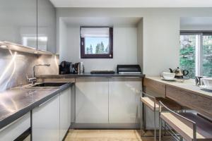 a kitchen with white cabinets and a sink at Résidence Les Sapins - Courchevel 1850 in Courchevel