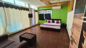 a bedroom with green walls and a bed with purple pillows at Vijay Gardens in Pulivendla