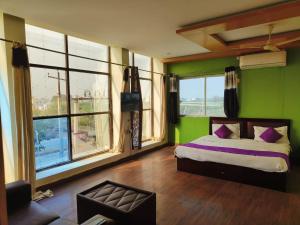 a bedroom with green walls and a bed with purple pillows at Vijay Gardens in Pulivendla