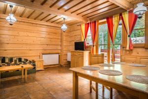 ein Wohnzimmer mit Holzwänden und Tischen sowie einem TV in der Unterkunft Chata Liptov in Liptovský Ján