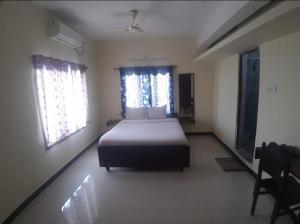 a bedroom with a bed and two windows at Renu Residency on the way to Isha yoga centre and near Maruthamalai in Marudhamalai