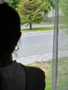 eine Person, die aus einem Fenster auf die Straße blickt in der Unterkunft SOUL B&B in El Calafate