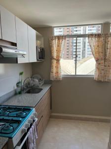 Il comprend une cuisine équipée d'une cuisinière. four supérieur à côté d'une fenêtre dans l'établissement Moderno Apartamento en Condominio Alto Venezuela, à Lima